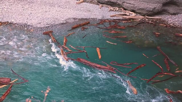 The flow of water carries the logs into the funnel. A stormy river washes away a forest, a flood.