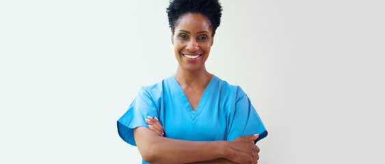 Portrait Of Mature Smiling Female Doctor Wearing Scrubs In Hospital With Copy Space