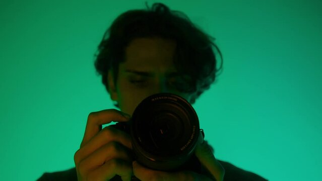 Professional male photographer working in studio. It uses colored neon lighting.