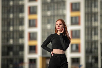 Portrait of a young beautiful red-haired girl in an urban environment.