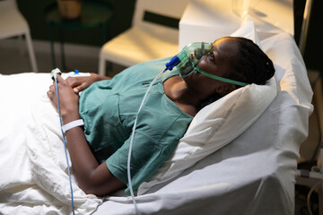 Shot of a woman in a hospital bed, African, with an oxygen mask, recovering from a lung-related...