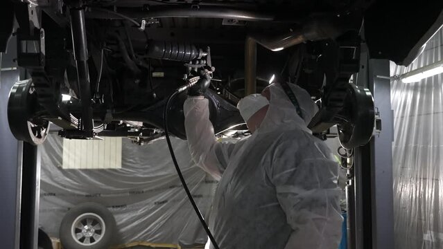 The master sprays an anti-corrosion compound on the bottom of the car. 