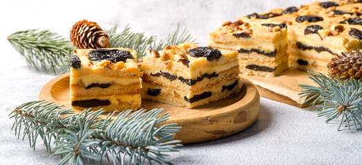 Cake with prunes and nuts. Pieces of delicious cake on a wooden plate. Decoration for the New Year...