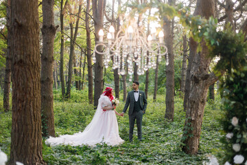 Beautiful couple, the groom in a green suit and the bride in an unusual pink wedding dress, posing...