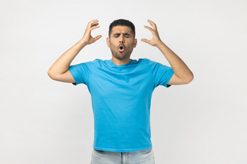 Portrait of shocked tired exhausted unshaven man wearing blue T- shirt standing showing mind...