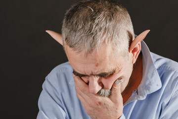 The old elf is sad in deep thought, resting his head on his hand with a cut finger.