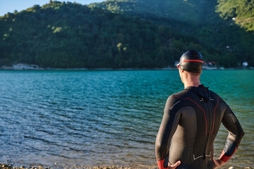 Authentic triathlon athlete getting ready for swimming training on lake