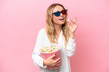 Young Russian woman isolated on pink background with 3d glasses and holding a big bucket of popcorns