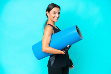Young caucasian woman isolated on blue background with a mat and smiling © luismolinero