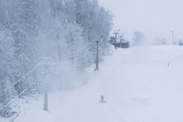 downhill skiing track with people lifting baskets in winter blowing snow