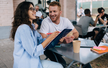 Fototapeta premium Cheerful colleagues working on project in cafe