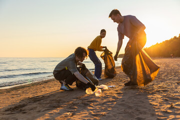 Earth day. Volunteers activists team collects garbage cleaning of beach coastal zone. Woman mans puts plastic trash in garbage bag on ocean shore. Environmental conservation coastal zone cleaning - obrazy, fototapety, plakaty