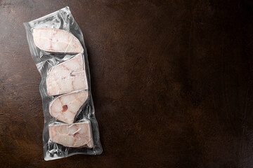 Frozen raw catfish steaks in vacuum packaging on a dark background copy space for text