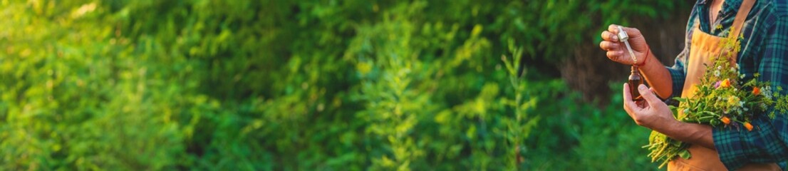 A man collects medicinal herbs in a field. Selective focus.
