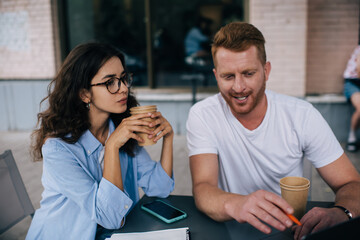 Young freelancers sitting with coffee cups in cafe