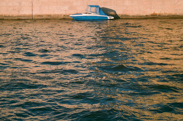 Obraz premium A blue boat reflected in the waves at sunset - film photography