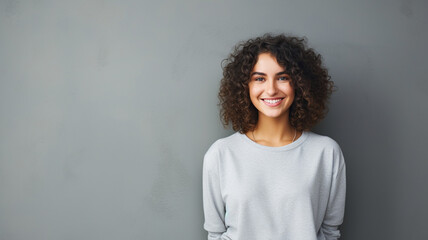 portrait of a happy young brunette woman with curly hair smiling isolated over gray background
