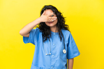 Young surgeon doctor asian woman isolated on yellow background covering eyes by hands and smiling