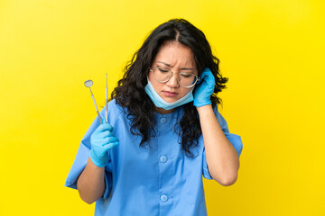 Young asian dentist holding tools over isolated background frustrated and covering ears