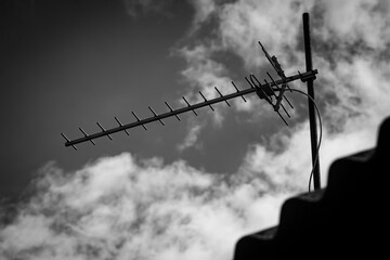 Television antenna on the roof of the house on the background of the sky with clouds - obrazy, fototapety, plakaty