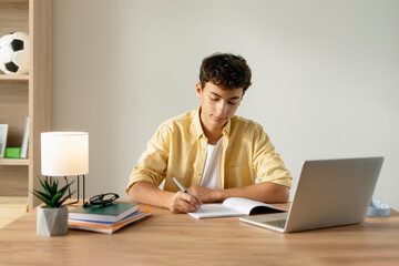 Smart serious teenage boy using laptop computer studying, learning language, exam preparation,...