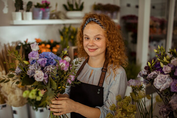 Smiling florist holding a fresh bouquet in her shop