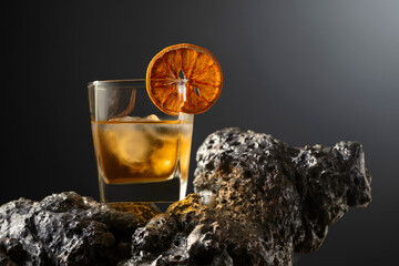 Old fashioned cocktail with ice and dried orange slice.