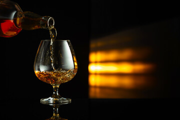 Pouring brandy from a bottle into a snifter.