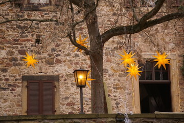 Gelbe Weihnachtssterne und gelbe Straßenlaterne vor einer Steinmauer in Deidesheim