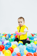 Fototapeta na wymiar Happy boy in colorful balls in children's playgroup. the child smiles, hiding in the balls.