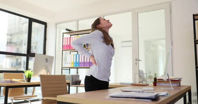 Woman holds with back with pain from incorrect sitting position