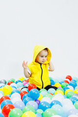Happy boy in colorful balls in children's playgroup. the child smiles, hiding in the balls.