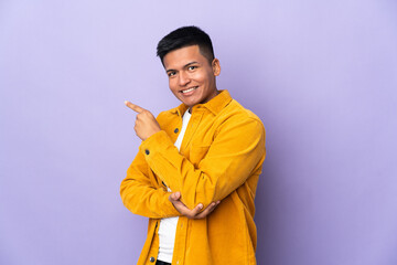 Young Ecuadorian man isolated on purple background pointing finger to the side
