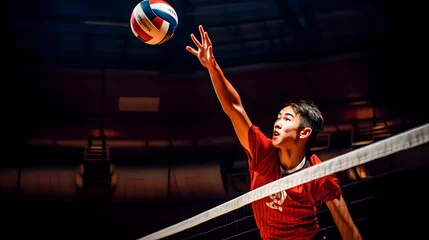 Fotobehang Asian volleyball player spiking over the net © TopMicrobialStock