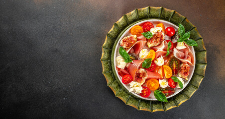 Tomato, figs and mozzarella salad on a dark background. Long banner format. top view - obrazy, fototapety, plakaty