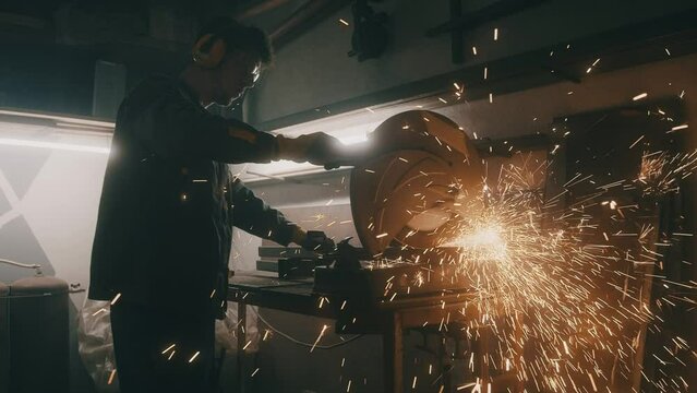 Man works circular saw. Industrial professional worker grinding metal. Craftsman sawing metal with disk grinder in workshop. Sparks fly from hot metal. Slow motion. 4K