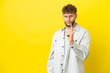 Young handsome caucasian man isolated on yellow background frustrated and pointing to the front