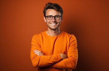 Fototapeta premium smiling man in orange sweater with arms crossed and smiling happy