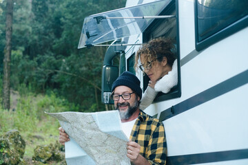 Traveler couple looking paper guide map with roads to choose next camper van journey destination....