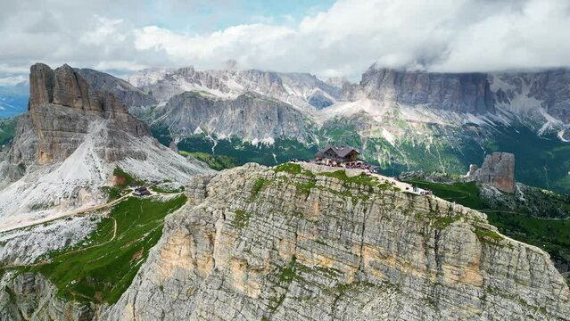 Aerial view of Rifugio Nuvolau, the oldest mountain hut refuge in the Dolomites, Italy. Clouds covering the mountains in the background. Beautiful destinations for hikers and alpinists. Cinematic shot