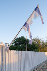 Remnants of the Israeli flag on a fence, weathered by wind and time, present an instant snapshot of...