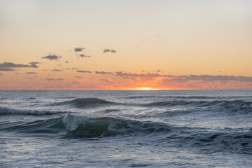 Naklejka premium The sea's waves on the sun set with a dramatic cloudy sky over the Mediterranean Sea. horizon with a warm, golden glow. magical tranquil seascape