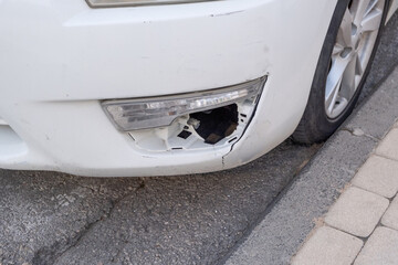 A broken damaged fog light on a car bumper, showcasing a minor form of damage often encountered in...