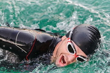 A professional triathlete trains with unwavering dedication for an upcoming competition at a lake,...