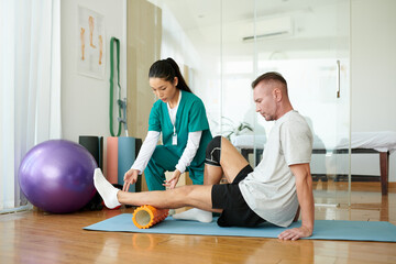 Rehabilitation specialist teaching patient how to do myofascial release for legs