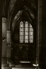 Saint Stephen cathedral interior. Arches, columns, antique stained glass window, candles and chandeliers light. Metz, France. Sepia historic photo.
