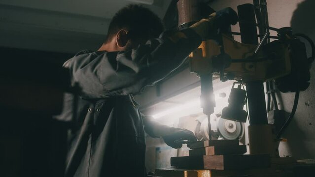 A worker works on a metal drilling machine in a workshop. Metallurgy production. A machinist operating a traditional non-CNC milling machine in a machine shop. Operates an industrial machine. 4K