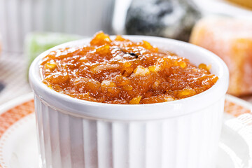 pot with homemade pumpkin jam, typical Brazilian dessert at the June and July parties, in the background fuba cake and candied sweets