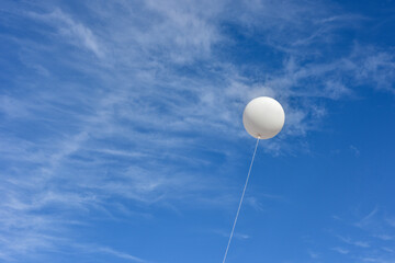 White balloon. A giant inflatable white advertising balloon floats in the sunny blue sky.