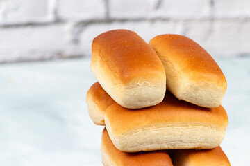 Some dinner rolls in Brazil are called "Bisnaguinha" filled with cheese and cream cheese on a white plate.